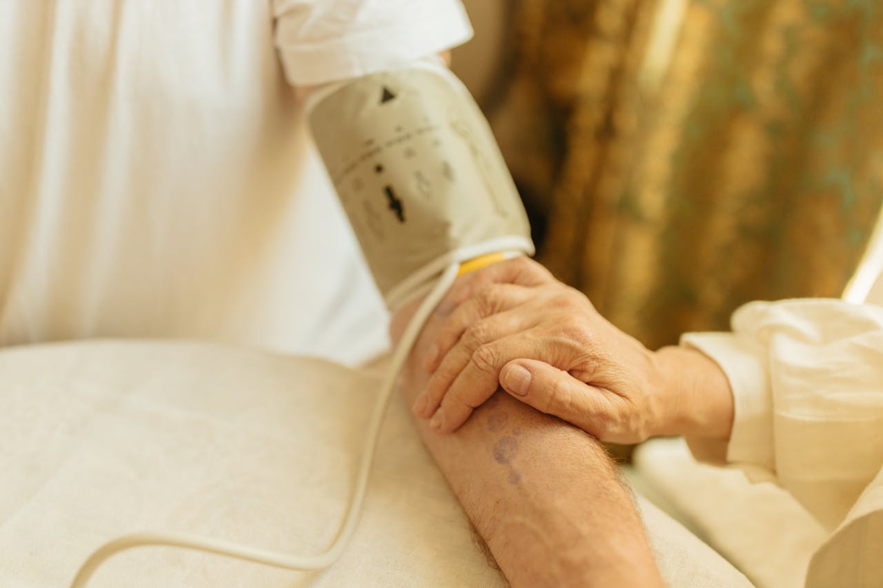 Close-up of a blood pressure measurement on a senior adult's arm indoors. Soft lighting.